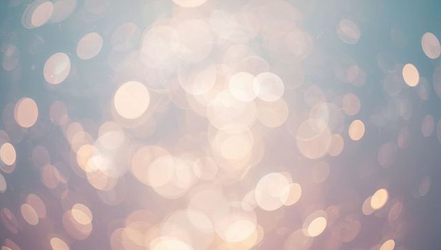 Glowing bokeh light orbs floating over soft teal peach cream gradient background