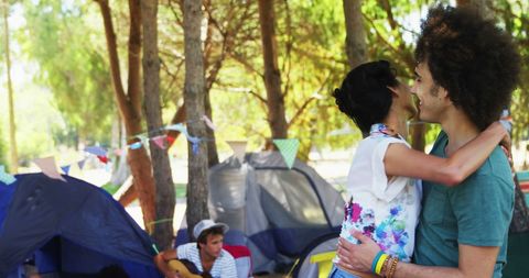 Young Couple Embracing at Campsite with Vibrant Outdoors Scene