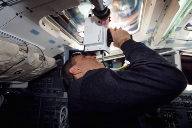 Astronaut uses a laser ranging device for measuring the distance between spacecraft aboard the Space Shuttle Columbia during the STS-109 mission in March 2002. Ideal for articles on space exploration, technology in space missions, NASA missions, and space shuttle operations.