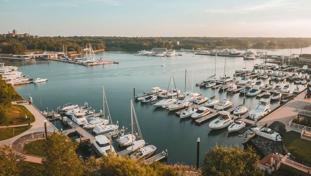 Marina featuring docked sailboats and luxury yachts at golden hour waterfront sunset panorama