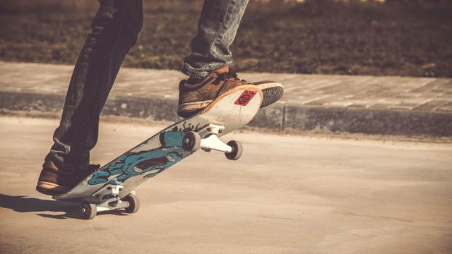 Person shown balancing on a skateboard in an outdoor setting. Ideal for topics on outdoor activities, youth lifestyle, extreme sports, energy, and physical activity. Suitable for articles, advertisements, and promotions related to skateboarding and sports equipment.