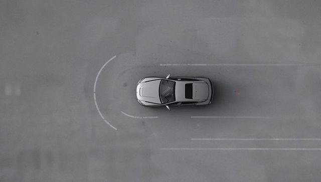 Top-down silver sedan on empty asphalt with curved lane markings and sunroof