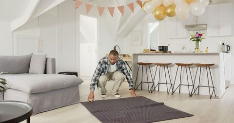Joyful Man Setting Up Home Anniversary Party with Balloons and Blankets