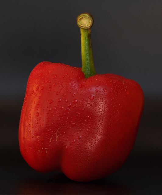 Red bell pepper covered in water droplets against a black background, showcasing its fresh and ripe condition. Ideal for use in food blogs, cooking websites, healthy eating promotions, and grocery store advertisements.
