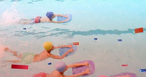 Kids practicing kickboard drills in pool wearing colorful caps and trunks, teamwork training session