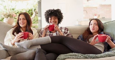Diverse female friends enjoying cozy time indoors on comfy sofa