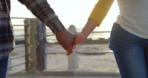 Interracial Couple Holding Hands on Sunny Beach Promenade