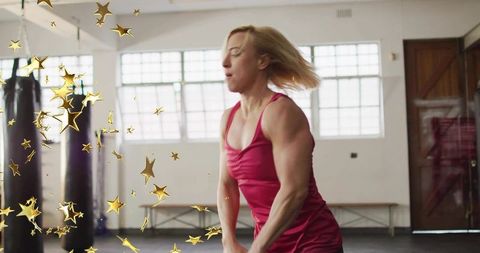 Female athlete training with punching bags and gold stars in boxing gym