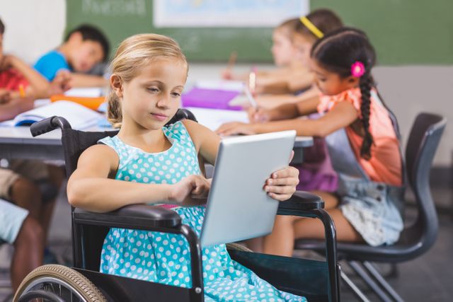 Young girl in wheelchair using a digital tablet while sitting in a classroom with her classmates. Ideal for use in education, technology, and inclusivity campaigns. Useful for illustrating concepts of accessible education, childhood learning, and the integration of technology in classrooms.