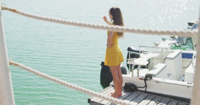 A woman in a yellow dress stands on a dock, pointing toward the expanse of the lake. boats are moored nearby, reflecting a serene, summer outdoor scene. This can be used for travel agency promotional materials, leisure lifestyle articles, vacation planning guides, or summer fashion features.