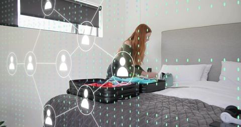 Woman packing suitcase in modern hotel room with digital network overlay, travel concept