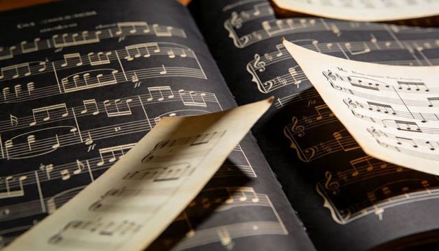Displaying vintage sheet music with curled parchment pages and warm golden lighting