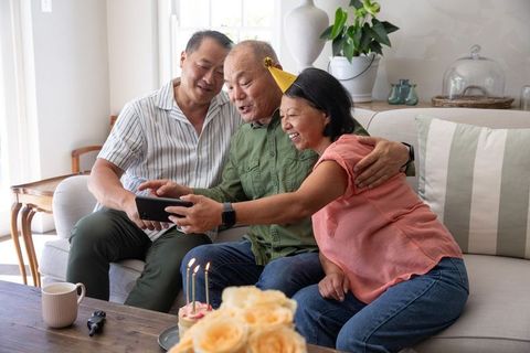Multigenerational asian family celebrating birthday and taking selfie with smartphone
