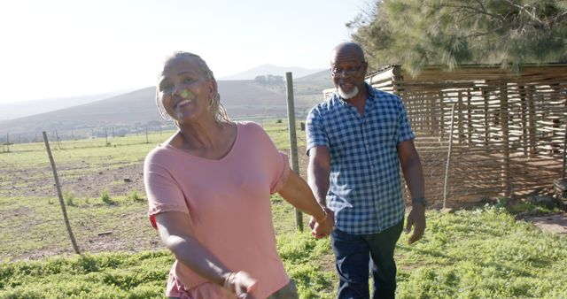 Happy senior african american couple holding hands walking in sunny garden. Retirement,wellbeing, summer and active senior lifestyle, unaltered,copy space.