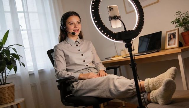 Livestreaming creator wearing headset and cozy loungewear in home office with ring light