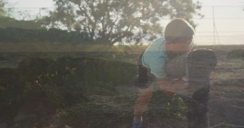 Boy climbing bollard at golden hour double exposure rural playful outdoor scene