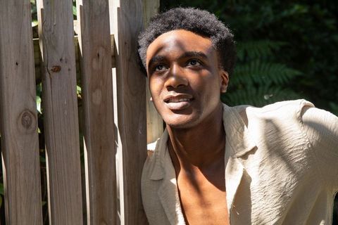 Relaxed man enjoying sunshine outdoors near wooden fence