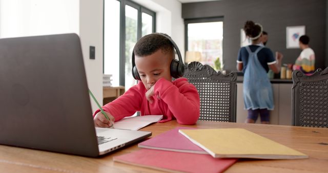 African american boy with headphones learning online using laptop at home. Lifestyle, learning, online education, communication, childhood and domestic life, unaltered.
