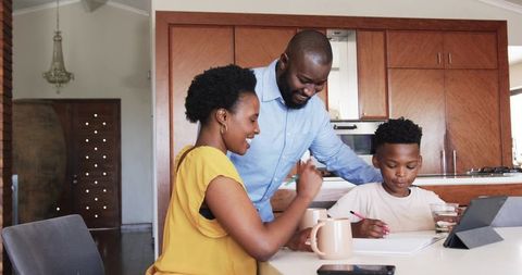 African American parents helping son with homework at kitchen island