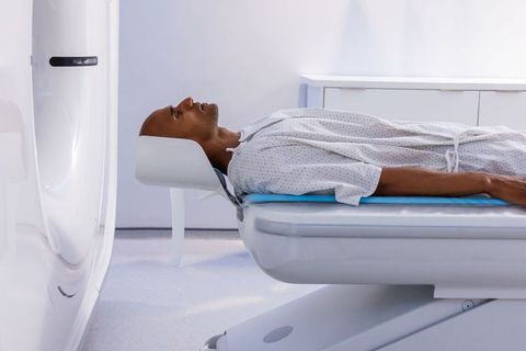 African american patient undergoing mri scan on motorized table in sterile radiology room