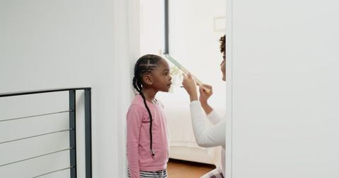Mother and Daughter Measuing Height Together at Home