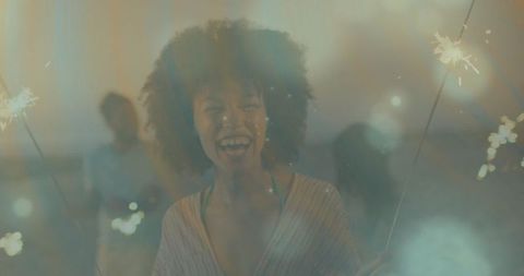 Joyful Young Woman Celebrating with Sparklers on Rooftop Terrace at Night