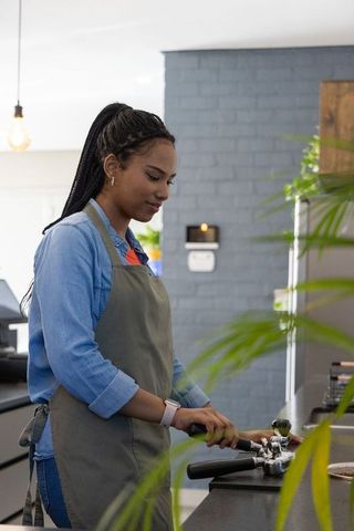 African American Barista Preparing Espresso with Portafilter and Tamper in Minimal Cafe
