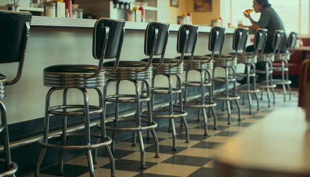 Retro diner counter with chrome stools and checkered floor, nostalgic cafe interior