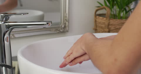 Person Washing Hands in Elegant Bathroom Setting