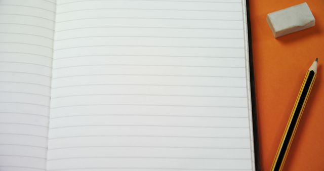 Open lined notebook next to a pencil and eraser on orange background, ready for writing or sketching. Could be used for education, study, back-to-school promotions, or content about writing and creativity.