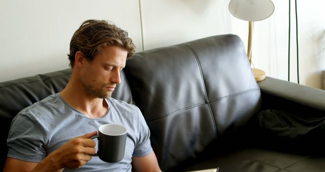 Man Reading Book and Drinking Coffee on Leather Sofa - Download Free Stock Images Pikwizard.com