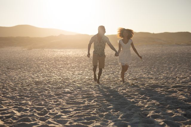 African American couple running on a beach, sunny sky in the background, Relationships and vacation. 