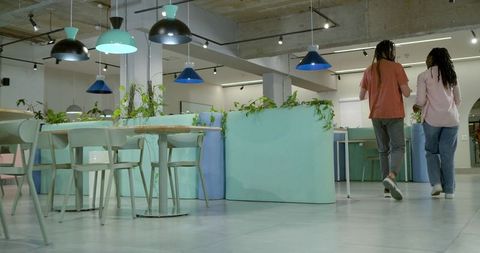 African american colleagues walking through modern coworking lounge with pastel planters