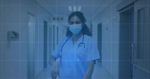 Nurse walking through hospital corridor in protective mask and scrubs