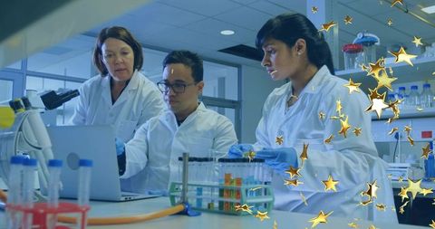 Researchers collaborating at laptop in biotech laboratory with test tubes and star overlay