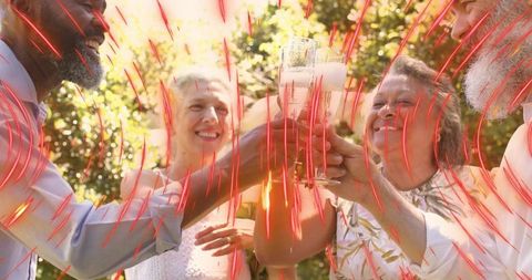 Mature friends toasting with champagne flutes in sunny backyard with red streak overlay