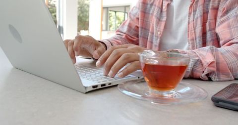 Man Working from Home with Laptop and Tea Playfully Nearby