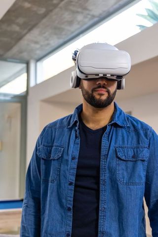 Man wearing white vr headset in modern office skylight, casual denim tech portrait