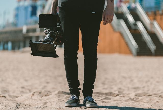 Perfect for illustrating the work-life of videographers, beach filmmaking projects, or promotional content for creative professionals. Can also be used in articles or websites discussing outdoor video production and filmmaking hobbies.