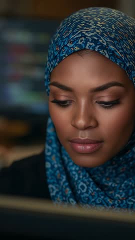 Vertical video: hijab-wearing student reading laptop, studying with calm focus closeup