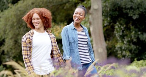 Happy couple walking hand in hand through sunlit garden