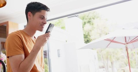 Smiling Man Enjoying Conversation on Smartphone by Sunny Garden