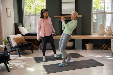 Home balance workout with personal trainer coaching active senior woman laughing and balancing