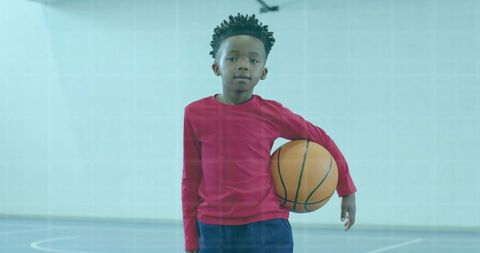Confident Young Boy with Basketball at Indoor Court