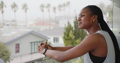 Contemplative woman on balcony with foggy urban view