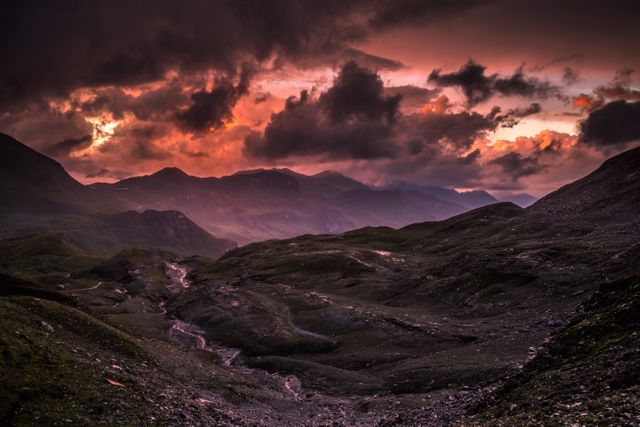 Dramatic sunset over mountainous landscape showcasing vibrant colors and dramatic shadows on rugged terrain. Perfect for nature enthusiasts, travel guides, landscape photography websites, and environmental conservation campaigns. Excellent for adding a visually striking element to adventure blogs and promotional materials.
