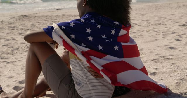 Young Person Wrapped in American Flag Sitting on Beach - Download Free Stock Images Pikwizard.com