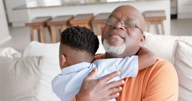 Happy african american grandfather and grandson hugging at home. Lifestyle, childhood, free time, family, togetherness and domestic life, unaltered.