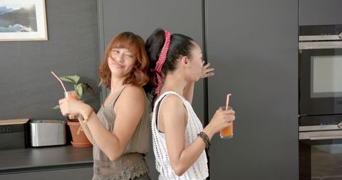 Two Friends Dancing and Enjoying Drinks in Modern Kitchen