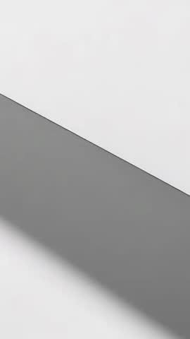 Vertical minimal video with sliding gray diagonal band casting soft shadow across pale wall